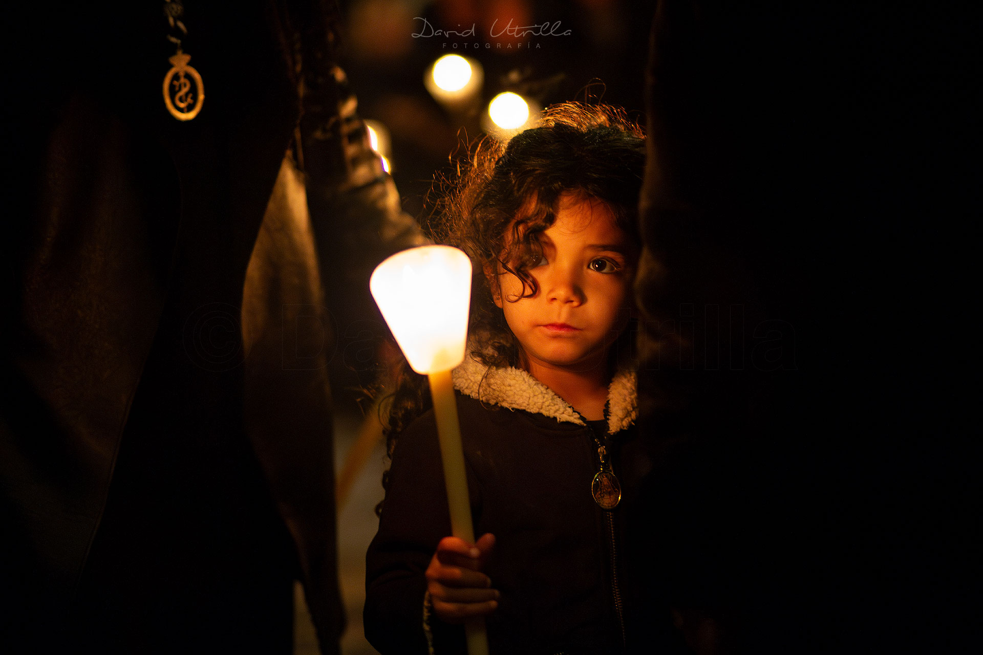 Una niña iluminada por una vela en una procesión de Semana Santa